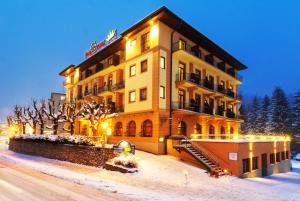 un grande edificio giallo nella neve di notte di Euro Youth Hotel & Krone a Bad Gastein