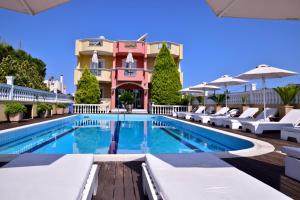 a swimming pool with white lounge chairs and a building at Hotel Cristina Maris in Loutraki