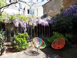 two chairs sitting in a garden with purple wisteria at Le Mans Chambre in Le Mans