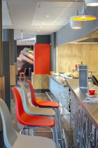 a restaurant with red and white chairs and a counter at ibis Cannes Mandelieu in Mandelieu-La Napoule