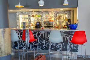 een bar met rode en witte krukken in een kamer bij ibis Cannes Mandelieu in Mandelieu-la-Napoule