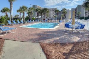 a swimming pool with blue chairs and a table and chairs at Pinnacle Port C1-203 in Carillon Beach