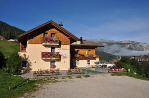 a building with flowers on the balconies of it at B&B Apartments La Palsa in San Cassiano