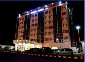 un gran edificio con coches estacionados frente a él en Hotel Sunshine Enugu, en Enugu