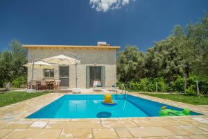 a villa with a swimming pool in front of a house at Alexandros Stone House in Nydri