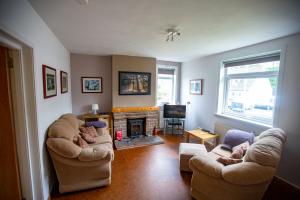 a living room with two chairs and a fireplace at Kelpies Cottage in Newton Stewart