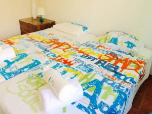 a bed with a colorful comforter and towels on it at Luxury Duplex with pool in Cabanas de Tavira