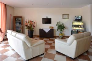 un soggiorno con 2 sedie bianche e una TV di Hotel Eolo a Sermide