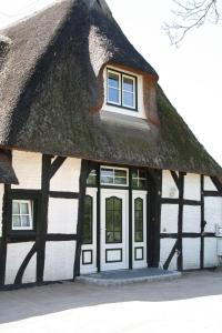 ein strohgedecktes Haus mit weißen Türen und Fenstern in der Unterkunft Schleisicht in Winnemark