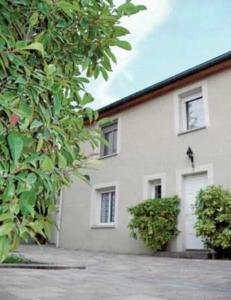 a white building with two windows and a bush at Les Berges de l'Ô in Saint-Nicolas-de-Port