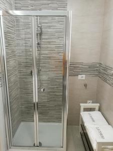 La salle de bains est pourvue d'une douche avec une porte en verre. dans l'établissement La Maison, à Margherita di Savoia