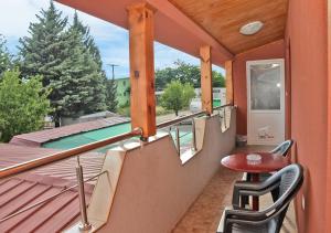 einen Balkon mit einem Tisch, Stühlen und einem Pool in der Unterkunft House La Strada in Negotino