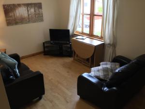een woonkamer met 2 stoelen, een bureau en een raam bij Culloden Apartment Free Parking in Inverness