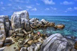 a person standing on rocks in the ocean at dric's House in Tanjungpandan