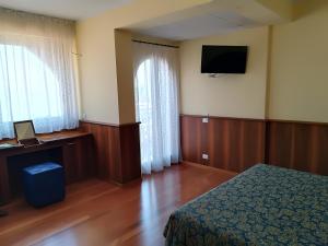 a bedroom with a bed and a television on the wall at Hotel Nike in Giardini Naxos