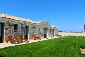 un edificio de piedra con bancos y un patio de césped en Agriturismo Masseria Quaremme, en Carpignano Salentino