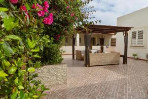 um pátio com uma pérgola e flores cor-de-rosa em Residence Agave Lampedusa em Lampedusa