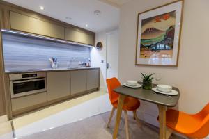 a kitchen with a small table and orange chairs at York Cocoa Suites in York