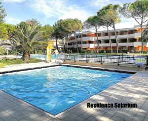 a swimming pool with blue water in front of a building at Residence Solarium bilo in Bibione