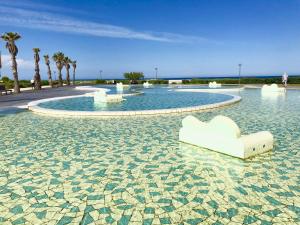 una piscina d'acqua con sedie bianche e palme di Barcaresa-MAISONNETTE VUE MER PIEDS DANS L'EAU WIFI a Port Leucate