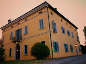 un gran edificio amarillo con persianas azules en R&B Villa Tartaruga, en Castelfranco Emilia
