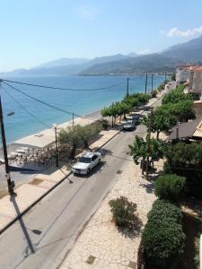 a street with a white car parked on a beach at Mondo Cosseri Akrata in Akrata