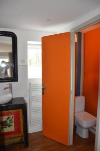 La salle de bains est pourvue de toilettes et d'une porte orange. dans l'établissement Ô Sources, à Bazenville