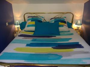 a bed with blue and yellow pillows on it at Au Bois de Massier - Chambre d'hôtes in Vienne