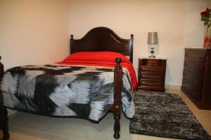 um quarto com uma cama com um cobertor vermelho e uma cómoda em Salvador Beach House I na Nazaré