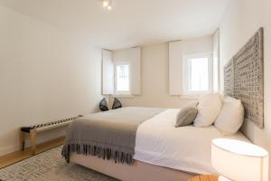 リスボンにあるFLH Martim Moniz Luxus Flatの白いベッドルーム(ベッド1台、窓2つ付)