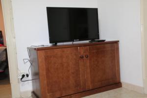 uma televisão de ecrã plano em cima de um armário de madeira em Salvador Beach House I na Nazaré