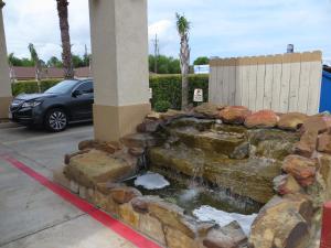 een stenen fontein op een parkeerplaats naast een auto bij Palace Inn Westheimer in Houston