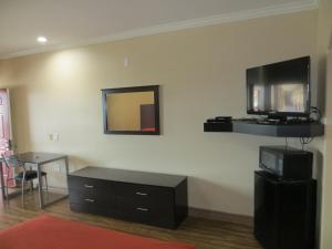 ein Wohnzimmer mit einem TV an der Wand und einem Tisch in der Unterkunft Palace Inn Westheimer in Houston