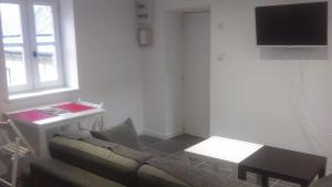 een woonkamer met een bank, een tafel en een televisie bij Studio Dumas in Bayeux