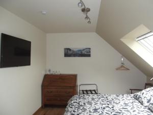 1 dormitorio con 1 cama, TV y vestidor en Au Bonheur Frontalier en Steenvoorde
