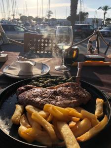 ein Steak und Pommes Frites auf einem Tisch mit einem Glas Wein in der Unterkunft La Manga Apartment Capri in La Manga del Mar Menor