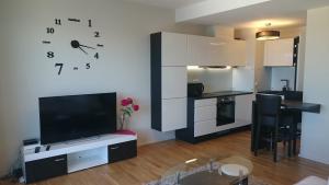 a living room with a large tv and a kitchen at Central Aida Apartment in Pärnu
