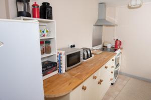 a kitchen with white cabinets and a wooden counter top at The Studio in Somerton