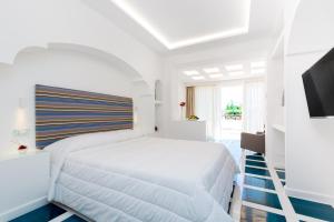 a white bedroom with a white bed and a television at Quattro Passi Relais in Nerano