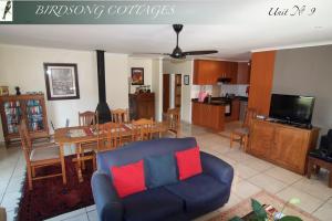 - un salon avec un canapé et une salle à manger dans l'établissement Birdsong Cottages, à Champagne Valley