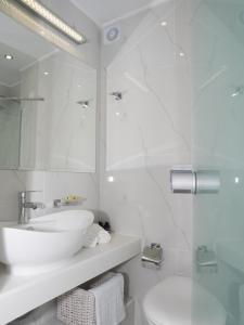 W białej łazience znajduje się umywalka i lustro. w obiekcie Amaryllis Beach Hotel w mieście Chrissi Akti