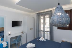 a room with a blue bed and a desk and a chandelier at B&B Reset confort & relax in San Vito lo Capo