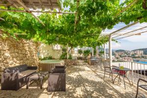 een patio met stoelen, tafels en wijnstokken bij Apartments Zore Glavinić in Dubrovnik