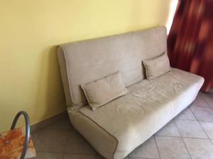 a couch with two pillows sitting against a wall at Liget apartman in Balatonföldvár