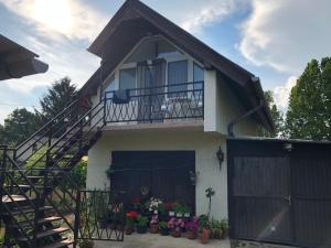 a house with a balcony and a gate and flowers at Liget apartman in Balatonföldvár