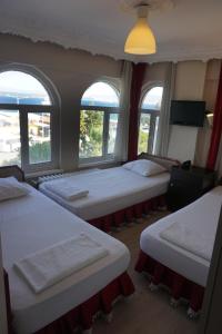 three beds in a room with three windows at Boss Hotel in Eceabat