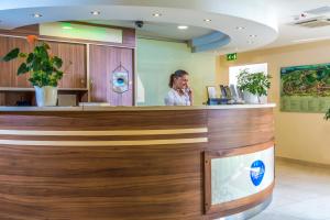 a woman standing at a reception counter in a hospital at Patak Park Hotel Visegr&aacute;d in Visegr&aacute;d