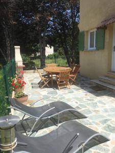 eine Steinterrasse mit einem Holztisch und Stühlen in der Unterkunft Villa Mer Et Montagne in Macinaggio