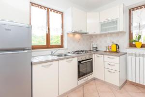 a white kitchen with a sink and a refrigerator at Apartments Radović in Labin