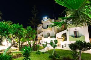 a large white building with palm trees in front of it at Sunshine Apartments in Kato Daratso